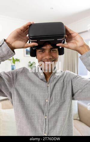 Portrait of happy biracial man using vr headset at home Stock Photo