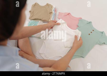 mother is folding baby clothes on a bed Stock Photo