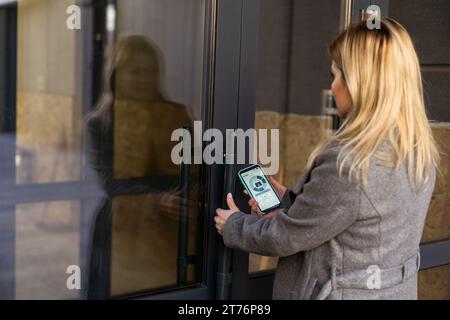 Middle aged woman pushing button of intercom Stock Photo