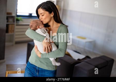 Loving mother carying of her newborn baby at home. Family parenting baby single mother love concept. Stock Photo