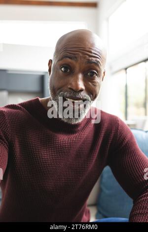 Happy surprised african american mature man having video call in sunny living room at home Stock Photo
