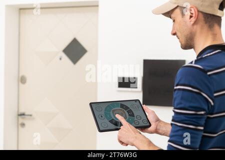 an electrician repairs an intercom with a tablet Stock Photo