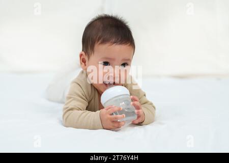 girl drinking bottle of milk laying on bed blond toddler Stock Photo - Alamy