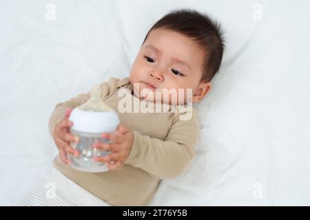 girl drinking bottle of milk laying on bed blond toddler Stock Photo - Alamy