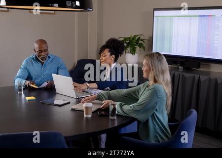 Happy diverse colleagues using laptops in meeting room Stock Photo