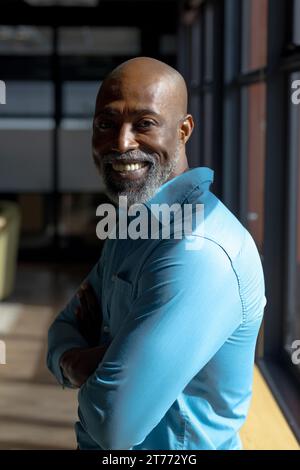 Portrait of happy senior bald african american casual businessman with beard smiling at office Stock Photo