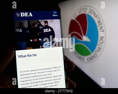 Person holding cellphone with webpage of United States Drug Enforcement Administration (DEA) in front of seal. Focus on center of phone display. Stock Photo