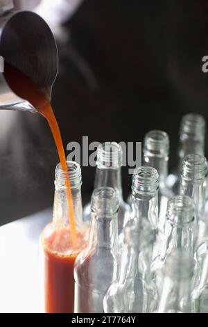 Tomato sauce being poured into a glass bottle Stock Photo