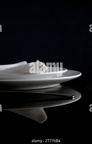 Close up of a place setting with plates and napkin on a glass table Stock Photo