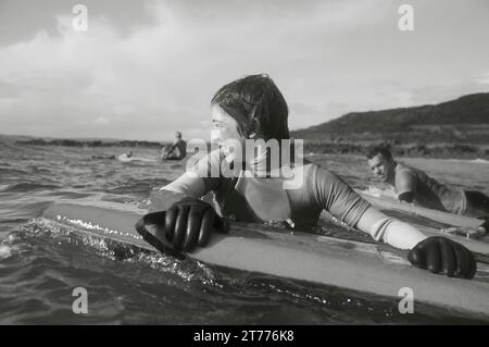 Teenaged boy in the sea holding on to his surfboard Stock Photo