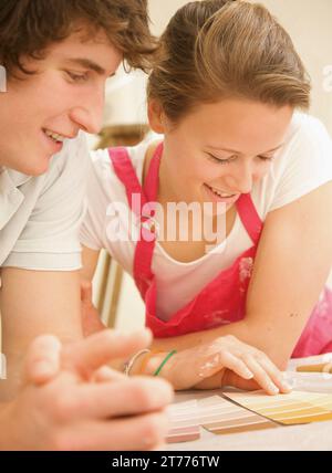 Couple leaning over a table looking at paint color swatches Stock Photo