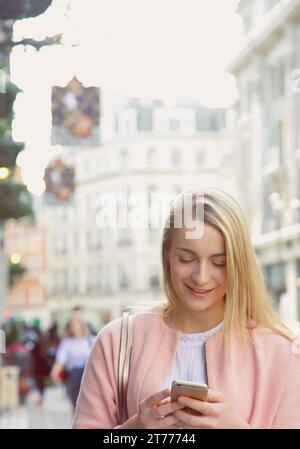 Young Woman Using Smartphone on City Street Stock Photo