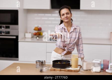 pretty woman showing plums for preparing plum pie in light kitchen Stock Photo