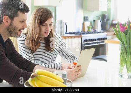 Couple Sitting at Table Using Digital Tablet Stock Photo