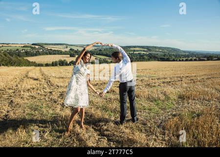 Couple in Field Holding Hands Making Heart Shape Stock Photo