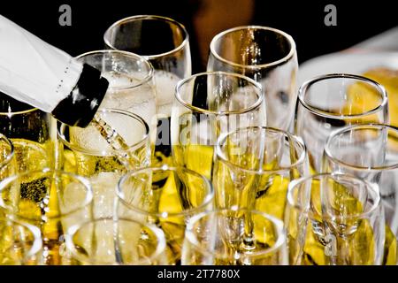 closeup of group of flutes of champagne on festive table and one is being filled Stock Photo