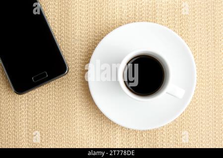 cup of coffee with smartphone on burlap surface Stock Photo