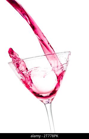 pouring a glass with red cocktail tilted and splashing on a white background Stock Photo