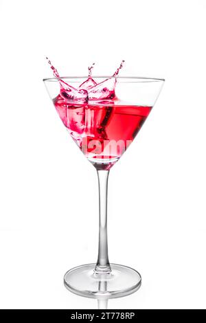 red dice falling in the red cocktail glass with splashes on white background Stock Photo