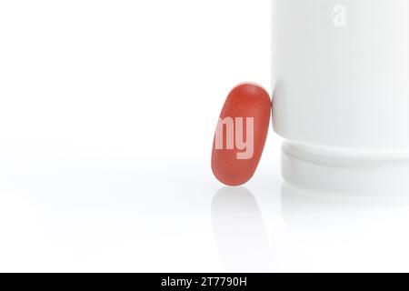 one red medical pill near white container on white background Stock Photo