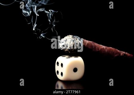 detail of one white dice and cigar with smoke on black background Stock Photo