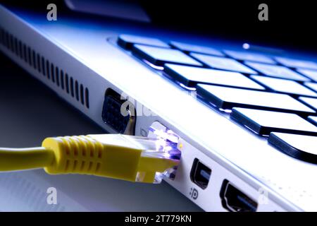 network cable plugged in the laptop as a background toned to blue Stock Photo