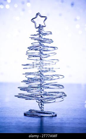 close-up of metallic modern christmas tree on wood table on blue tint light bokeh background Stock Photo