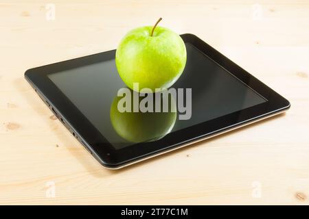 green apple on digital tablet pc on wood table, concept of learn new technology Stock Photo