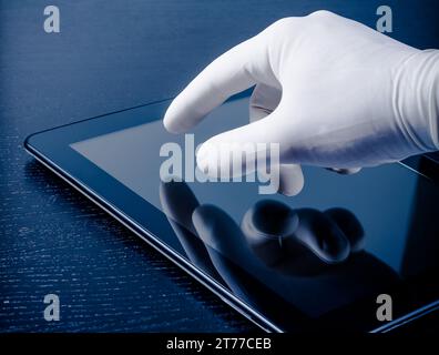 hand in medical glove touching modern digital tablet pc on wood table. Concept of medical or research theme Stock Photo