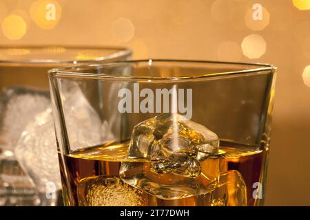 close-up of whiskey glasses on gold bokeh background Stock Photo
