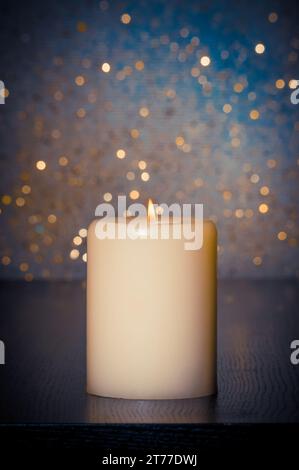 candle with flame on wood table and blue bokeh background and space for text Stock Photo