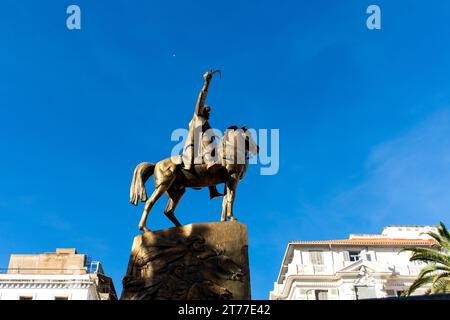 Low-angle view of Emir Abdelkader's statue against a blue sky in Algiers City. Stock Photo