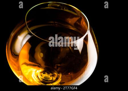 snifter of brandy in elegant glass with space for text on black background Stock Photo