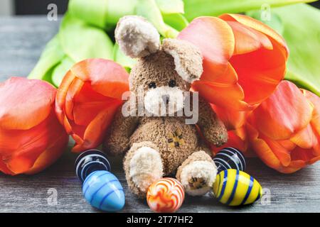 Easter bunny with Easter eggs and tulips on gray background Stock Photo