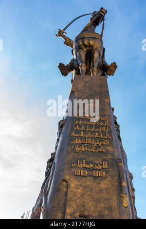 Low-angle view of Emir Abdelkader's statue against a blue sky in Algiers City. Stock Photo