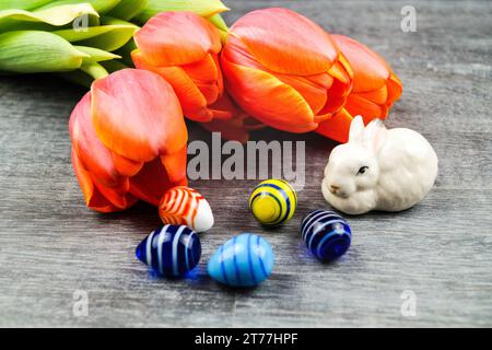 Easter bunny with Easter eggs and tulips on gray background Stock Photo