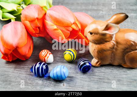 Easter bunny with Easter eggs and tulips on gray background Stock Photo
