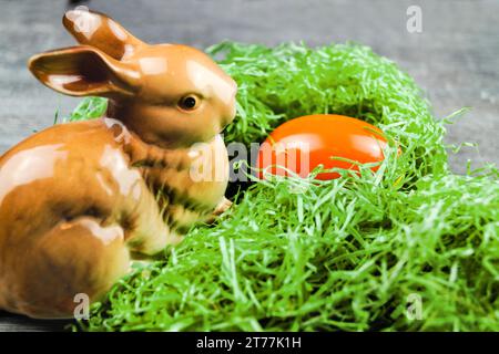 bunny figure with Easter egg in Easter nest on gray Stock Photo