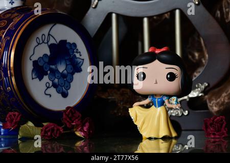 Funko Pop action figure of Disney princess Snow White with bird. Beautiful palace,  fabulous kingdom, columns, red roses, vintage blue keg. Stock Photo