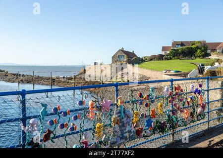 Colourful knitting in the shape of fish and marine life on a fence at Lower Largo, Fife, Scotland Stock Photo