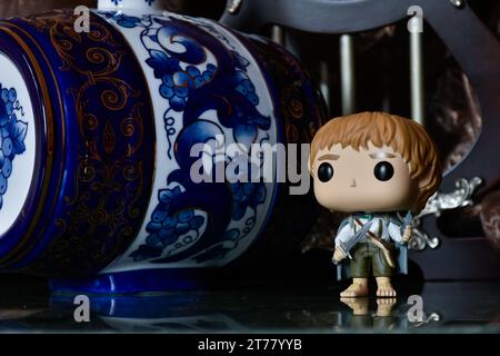 Funko Pop action figure of hobbit Sam from fantasy movie The Lord of the Rings. Dark palace, ancient columns, porcelain blue keg with patterns. Stock Photo