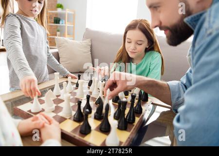 Portrait of lovely intellectual focused family playing chess with dad spending holiday free spare time at home house living-room indoors Stock Photo