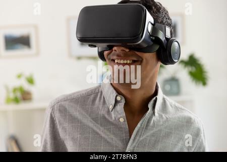 Happy biracial man using vr headset at home Stock Photo
