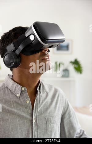 Happy biracial man using vr headset at home Stock Photo