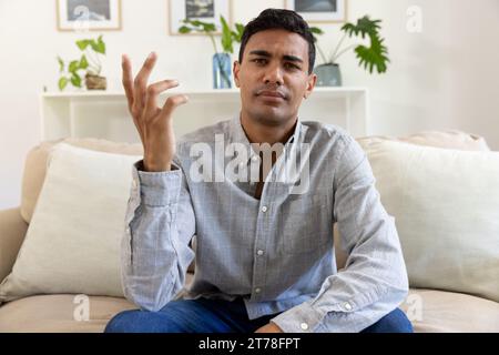 Biracial man sitting on sofa having video call at home Stock Photo