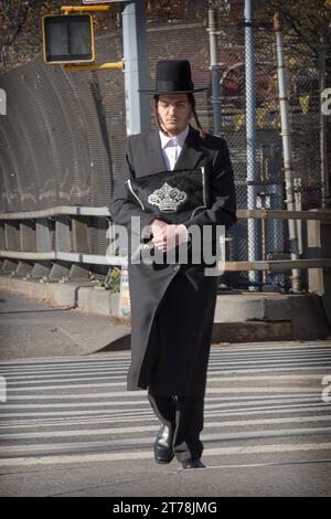 An orthodox Jewish man returns from morning services holding his tallis bag, In Brooklyn, New York on a cold autumn day in 2023. Stock Photo