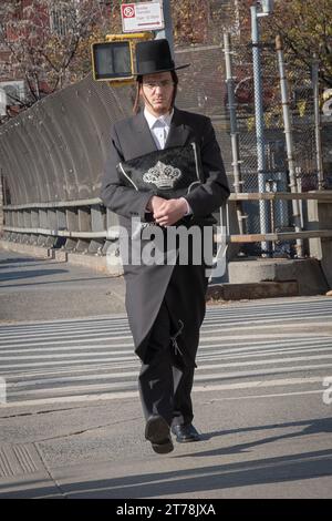 An orthodox Jewish man returns from morning services holding his tallis bag, In Brooklyn, New York on a cold autumn day in 2023. Stock Photo