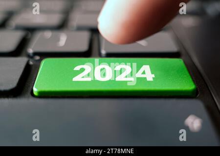 Keyboard with text 2024 year and finger pushing the enter button. Color button on the gray silver keyboard of modern ultrabook. caption on the button. Stock Photo