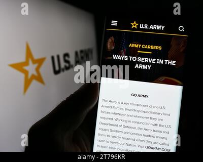 Person holding cellphone with webpage of United States Army in front of star logo. Focus on center of phone display. Stock Photo