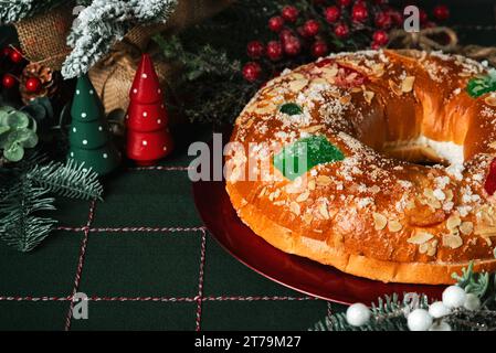 Roscon de reyes with cream on a red plate and christmas ornaments on a christmas tablecloth. Kings day concept spanish three kings cake.Typical spanis Stock Photo